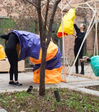 students in performance piece involving colored paper sleeves and wooden structure