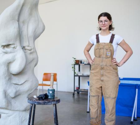 shanie tomassini standing arms on hips next to sculpture