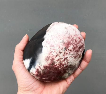 handheld stone with colors of black white and maroon 