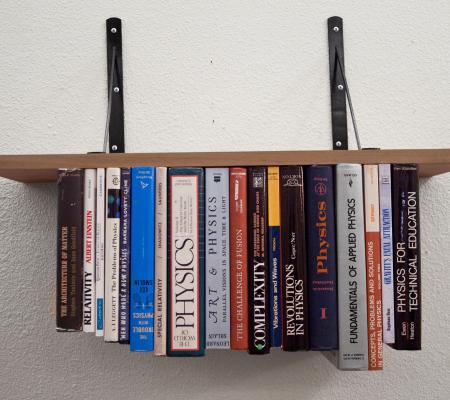 books on a bookshelf defying gravity by being upside down in a work by artist Rebecca Marino
