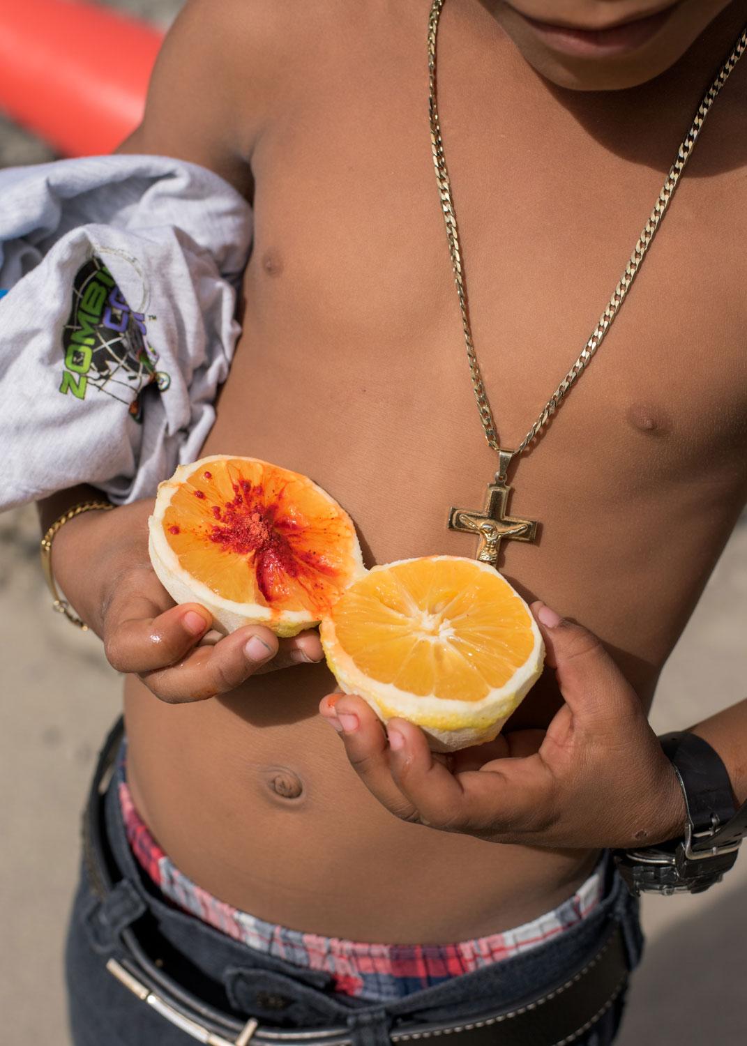 person holding two orange halves to chest under breasts