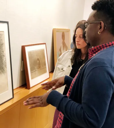 two people looking at and discussing framed prints on shelf