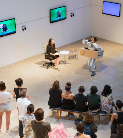 person with megaphone performing in front of a crowd in gallery