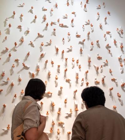 two people looking at small sculptural objects on gallery wall
