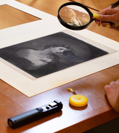 person using magnifying glass to view historical print