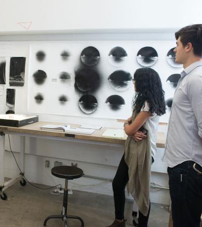 two people looking at art on wall in studio