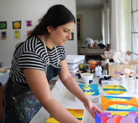 Print Studio Art Professor at The University of Texas at Austin Beverly Acha in Miami at the Fountainhead residency arranging her painting and print work in front of a window facing toward the right
