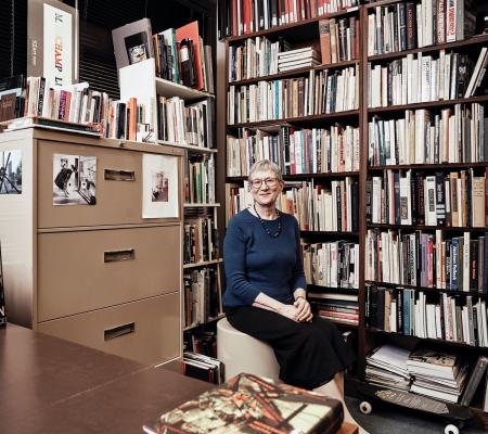 linda henderson seated in front of her bookcase within her faculty office