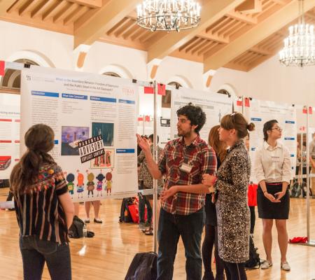 image of poster session with male student discussing research and poster with female audience