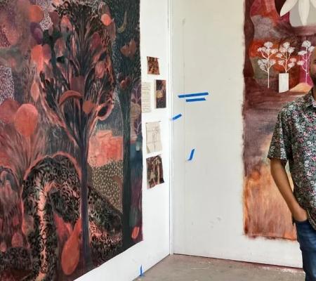 Man standing in front of painting of red and black hues