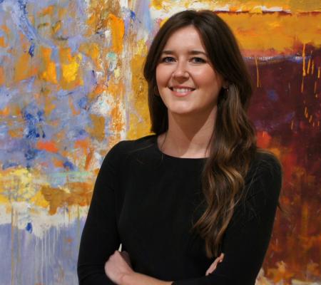 portrait of a woman with long brown hair in front of an abstract canvas painting