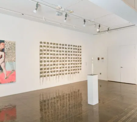 installation image of Beili Liu wall piece with concrete masks mounted to white wall and foregrounding that work is another from University of Texas at Austin BFA alumna Virginia Lee Montgomery VLM marble ponytail sculpture on a white plinth