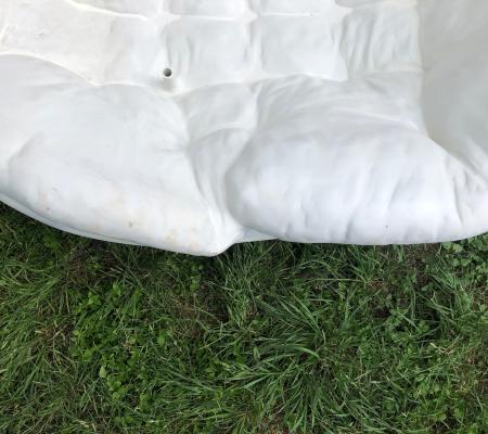 partial image of a hard solid sculpture made to look a soft cushion on grass