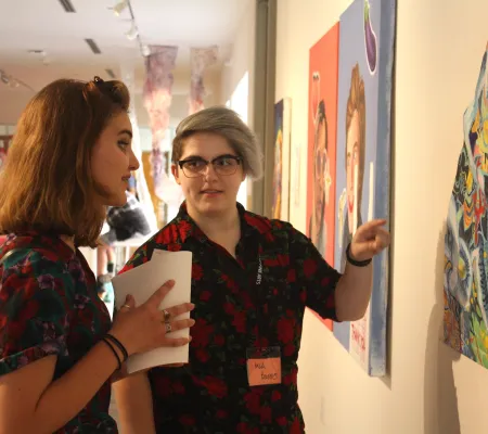 two people looking to the right side of the image and discussing a work of art