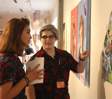 two people looking to the right side of the image and discussing a work of art