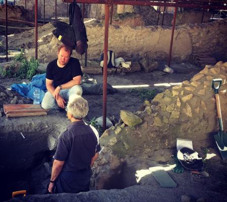 two men conversing within the site of an archaeology dig