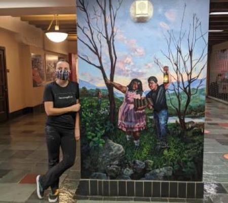 University of Texas at Austin studio art BFA graduate Roxolana Krywonos in front of her mural in the Texas Union hall 