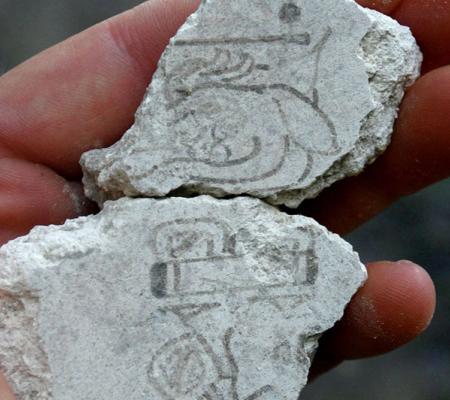 hand holding stone with engraved glyph