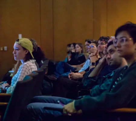crowd of students and teachers in a lecture hall looking toward speaker