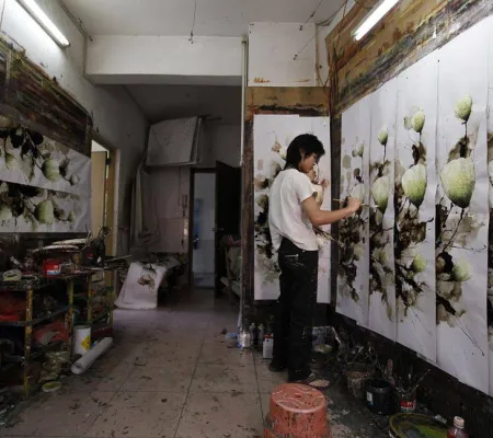 image of a woman in black pants and a white shirt painting multiple prints along a wall
