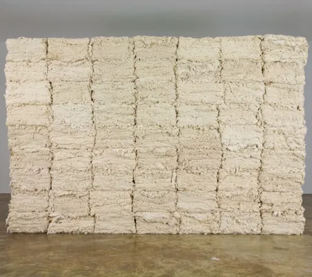 stacks of cotton like sheets arranged into a cubed formation in a gallery by Leonardo Drew Number 25