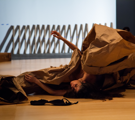 image of an artist performing a piece under tarp of large brown paper