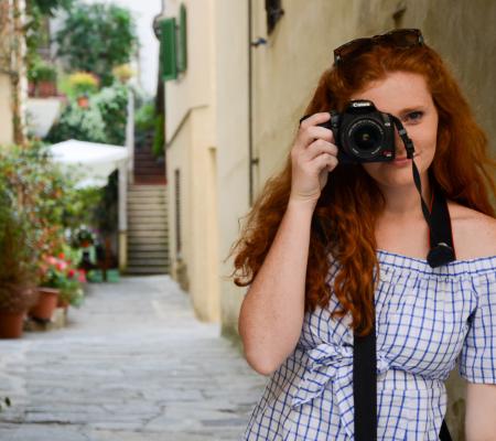 redheaded woman holding a camera up to one eye