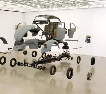 photo of disassembled car hanging in gallery