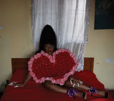 person laying on bed holding red and pink heart piece