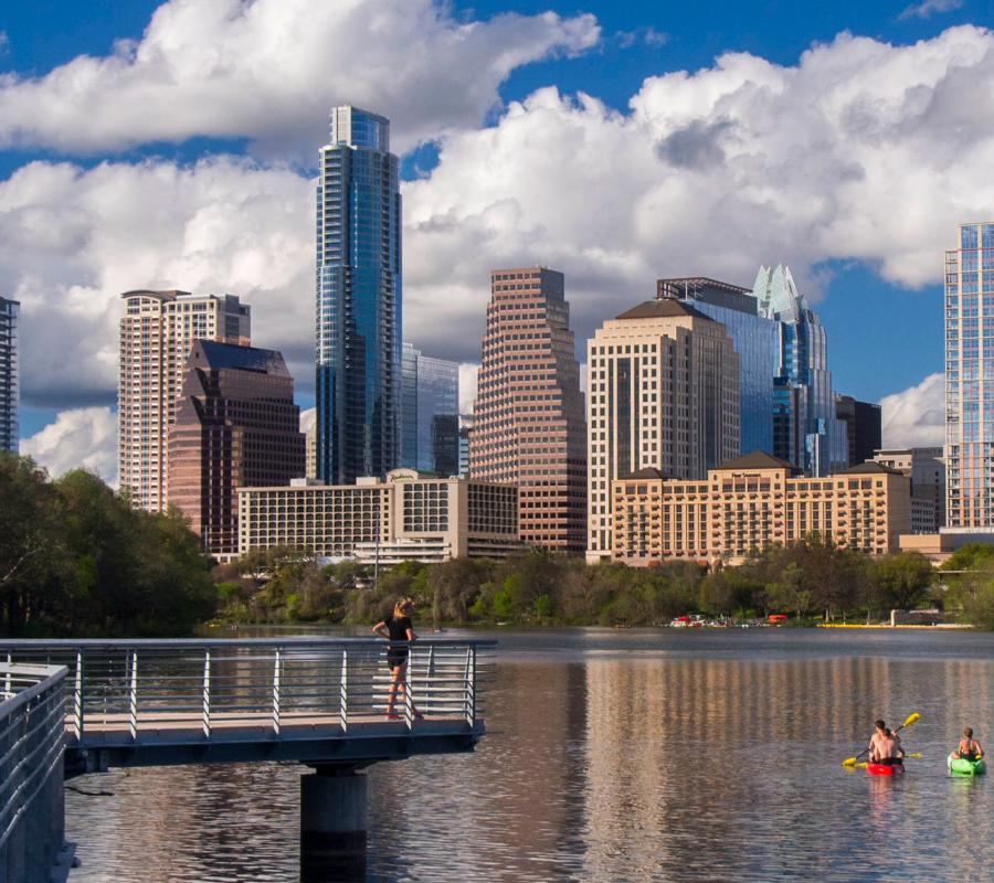 pedestrians on Town Lake boardwalk with Austin skyline in distance