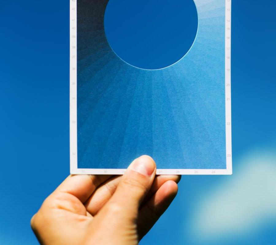 image of hand holding blue postcard against sky