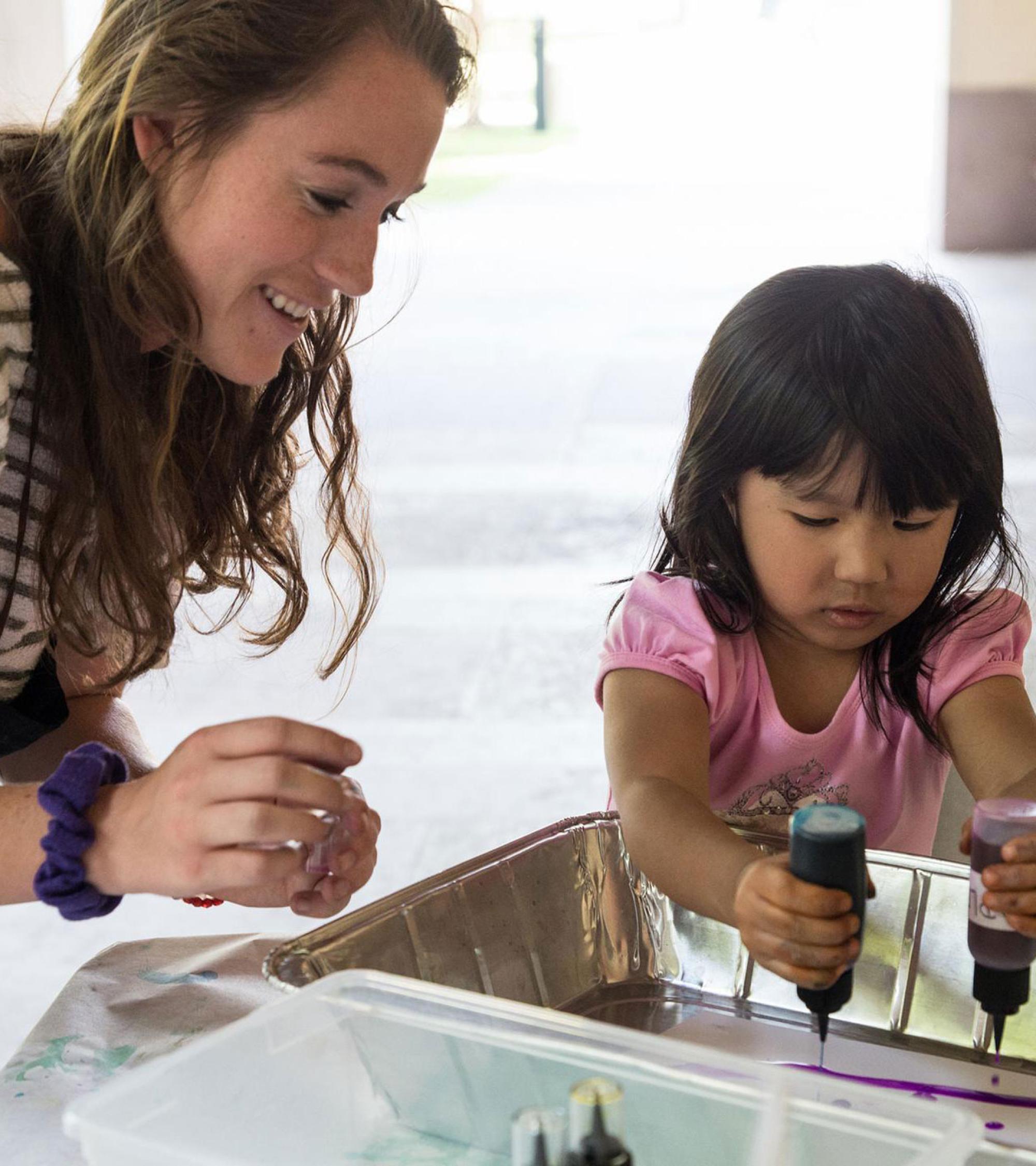 adult educator helping child with art supplies