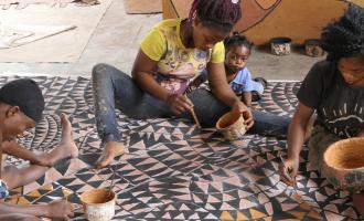 females painting canvas on ground