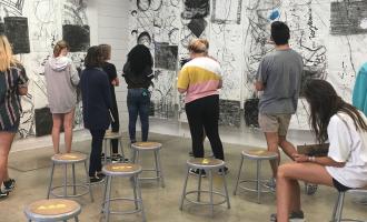 student looking at drawings on a wall in classroom