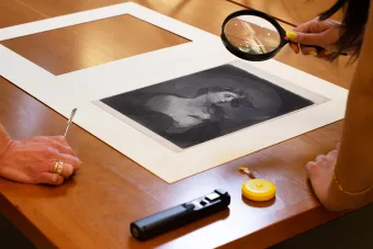 student looking at historical print through a magnifying glass