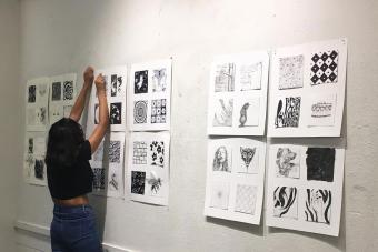 student pinning work onto the wall