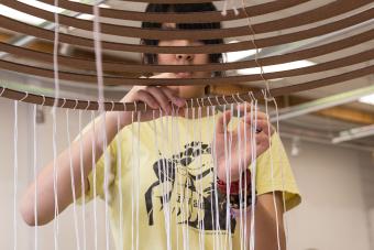 student working on sculpture made of cardboard and string