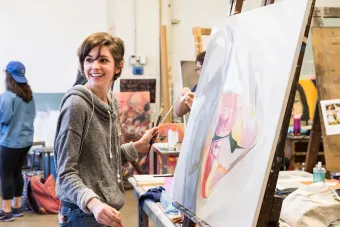 student at painting easel in classroom