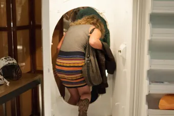 person stepping through hole in refrigerator in art exhibition