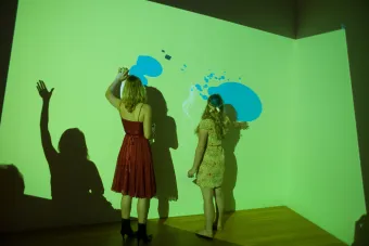 students interacting with projection on gallery wall
