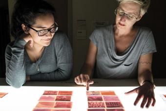 two people looking at film negatives on light table