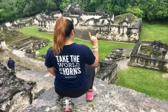 student in Longhorn short posing on pyramid in jungle