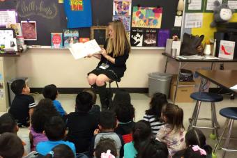 college student reading to elementary students in classroom