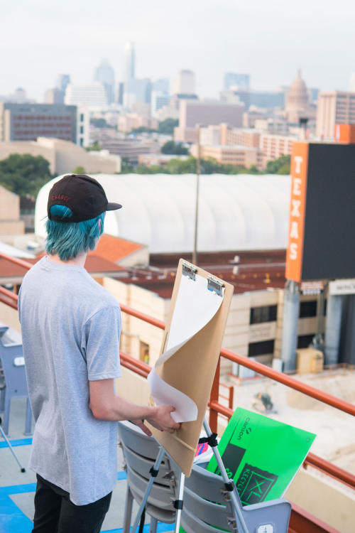 student drawing at easel overlooking UT football field