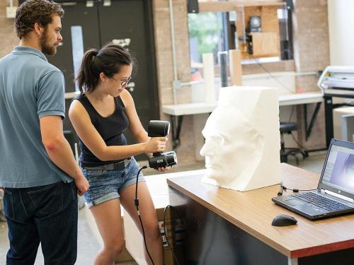 student using hand-held 3D scanner to capture sculptural bust