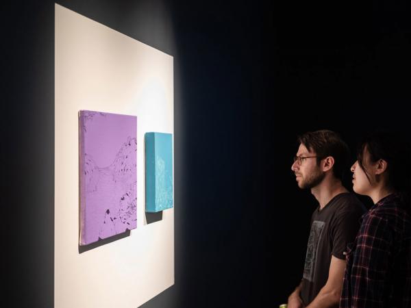 two people looking at art on wall in gallery