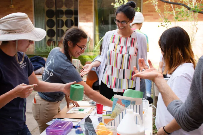 people standing around table containing art supplies