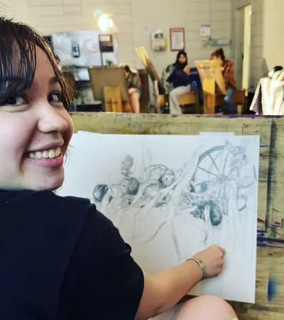 young person drawing at easel in classroom