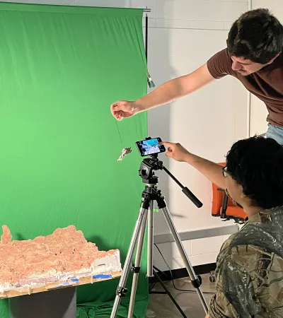 students photographing model in front of green screen