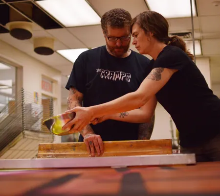 two printmakers working together on neon large scale print installation